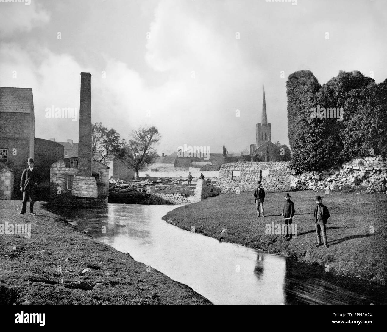 Vue de la fin du 19th siècle sur Athenry, une ville du comté de Galway, en Irlande. Les coulées de la rivière Clarin passent par les murs de la vieille ville et les bâtiments industriels récemment construits. La collégiale Sainte-Marie du milieu du 13th siècle peut être vue en arrière-plan; elle a été en grande partie détruite, mais en 1828 une église de l'Irlande a été construite dans son chœur. Banque D'Images