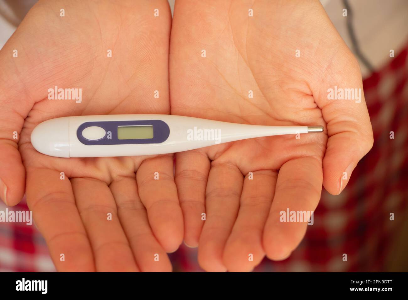 les mains des femmes tiennent un thermomètre électronique Banque D'Images