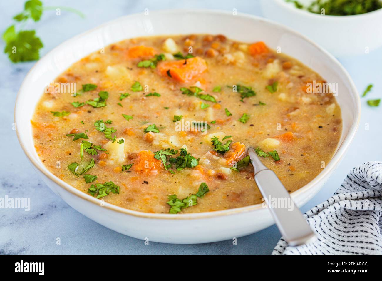 Ragoût de légumes avec pommes de terre, patate douce et lentilles dans un bol blanc. Recette basée sur l'usine. Banque D'Images