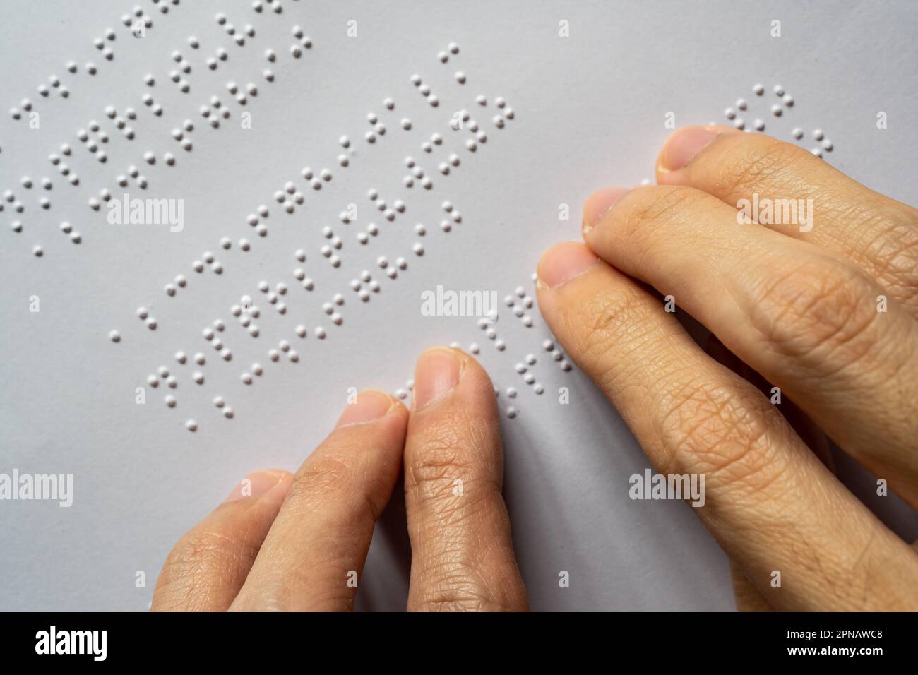 Personne aveugle lisant le livre. Les lettres en braille d'un paragraphe sont De A à Z et de 1 à 0 par ordre alphabétique. Banque D'Images