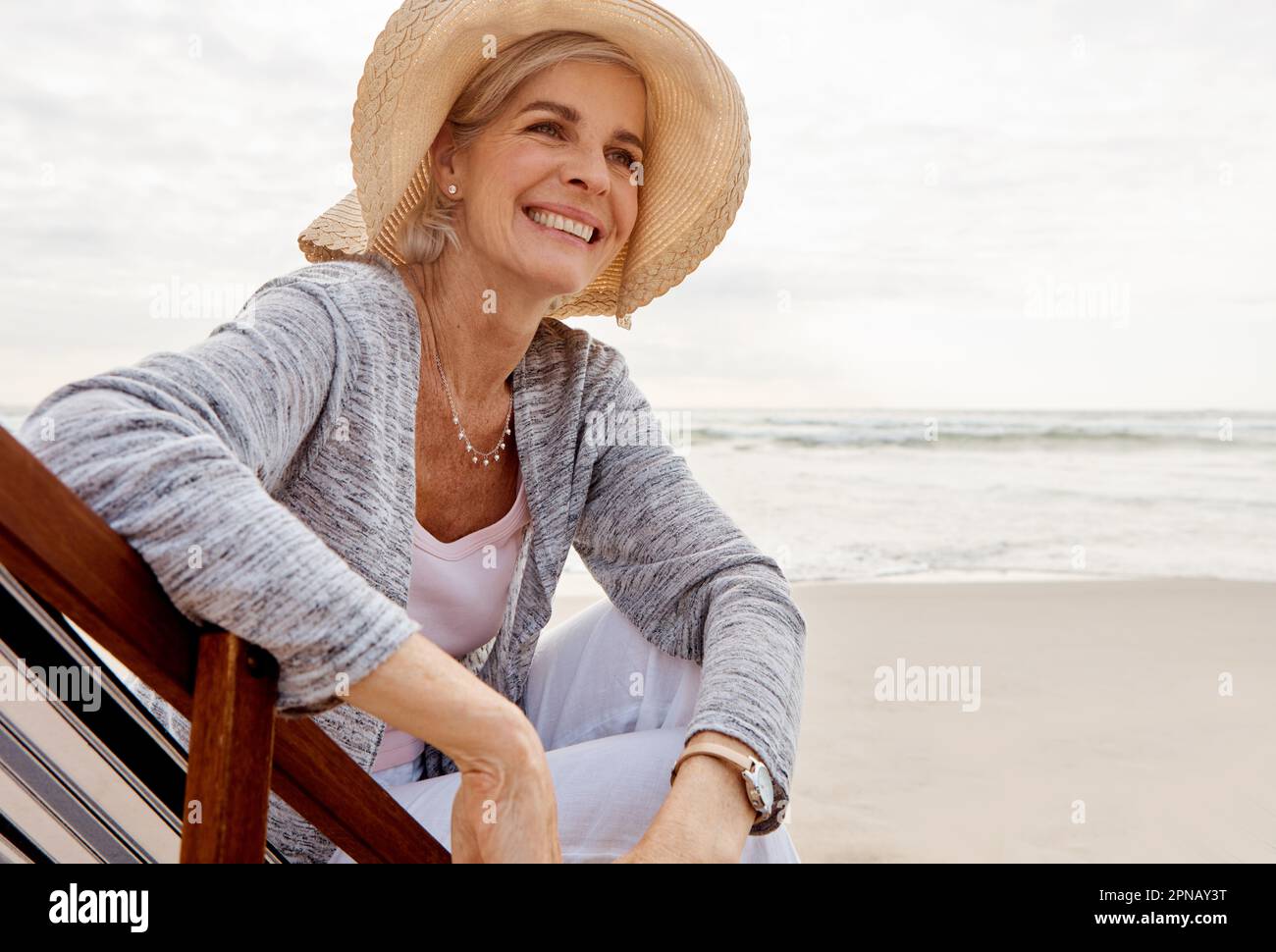 C'est merveilleux à la plage. une jolie femme d'âge moyen assise sur un transat à la plage. Banque D'Images