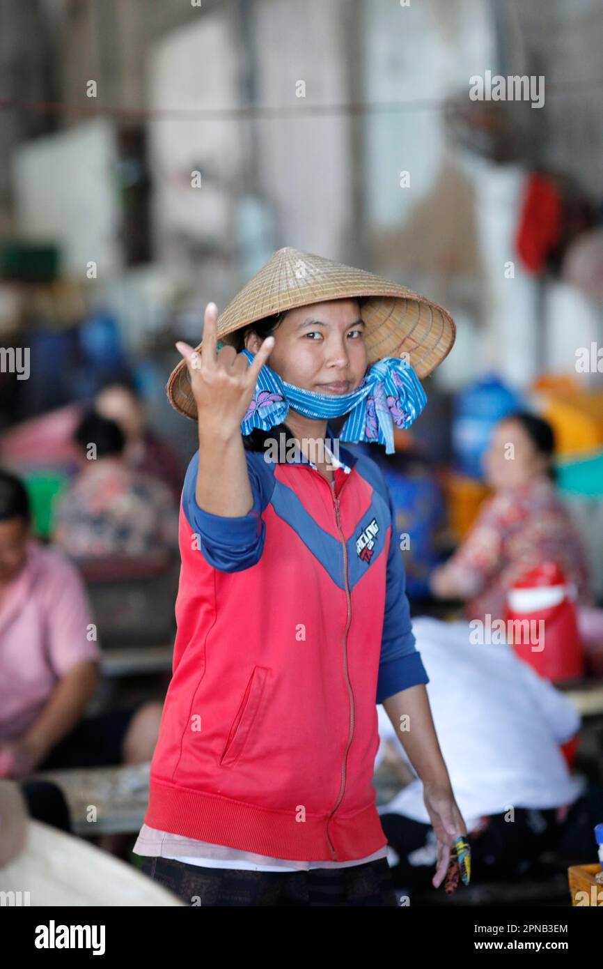 Femme avec le chapeau conique vietnamien traditionnel travaillant dans une usine de poisson. Tau. Vietnam. Banque D'Images