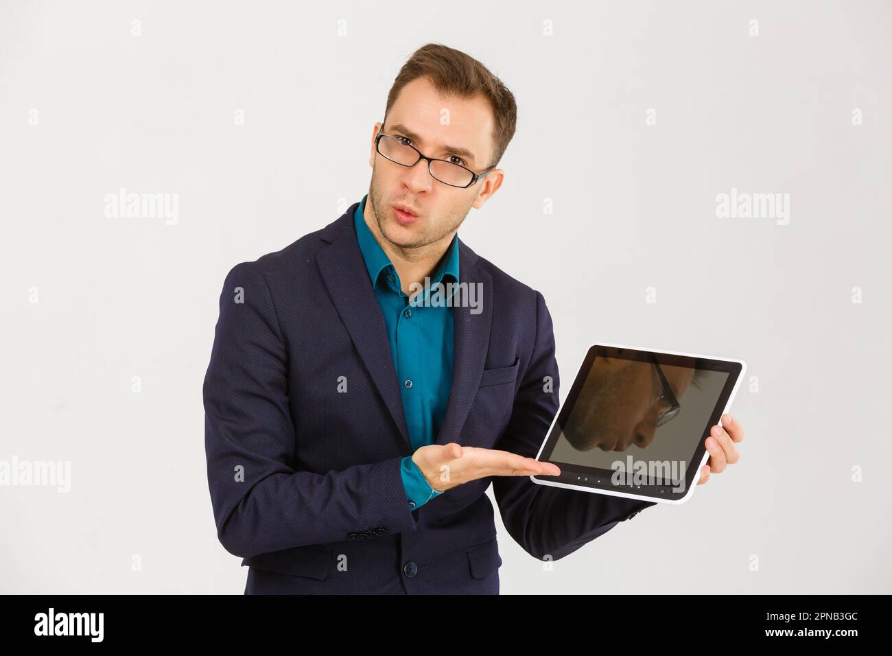 Jeune homme tient une tablette tactile sur fond blanc isolé. La tablette  numérique de grande taille