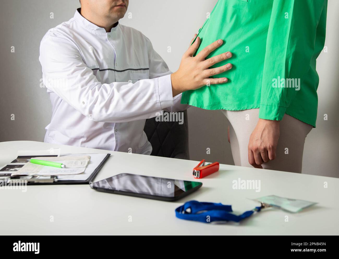 Le médecin obstétricien gynécologue de sexe masculin palpate le ventre d'une fille enceinte. Le concept de l'observation de la grossesse par un médecin. Dépistage et test de Banque D'Images