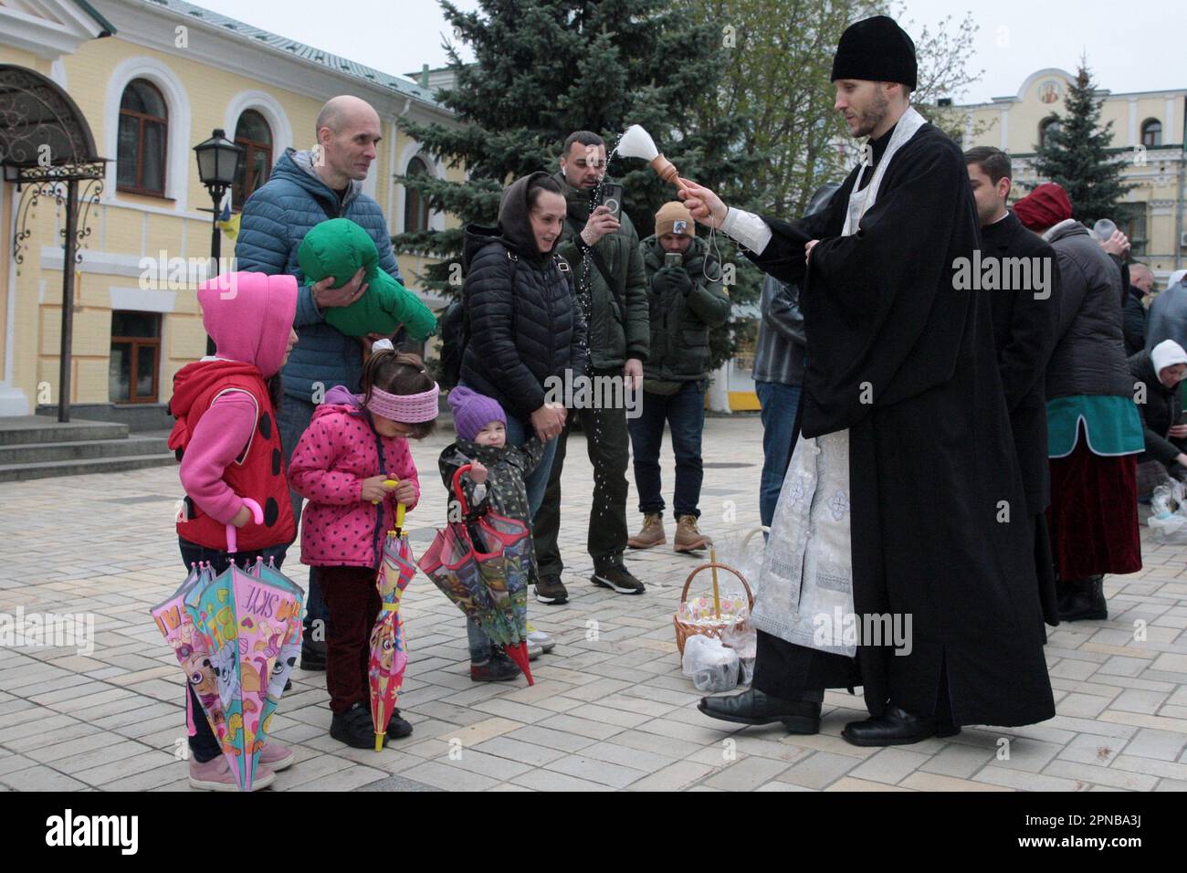 KIEV, UKRAINE - le 15 AVRIL 2023 - Un prêtre bénit les adultes et les enfants et leurs paniers de Pâques devant la cathédrale Saint-Michel, le Saint-Sam Banque D'Images