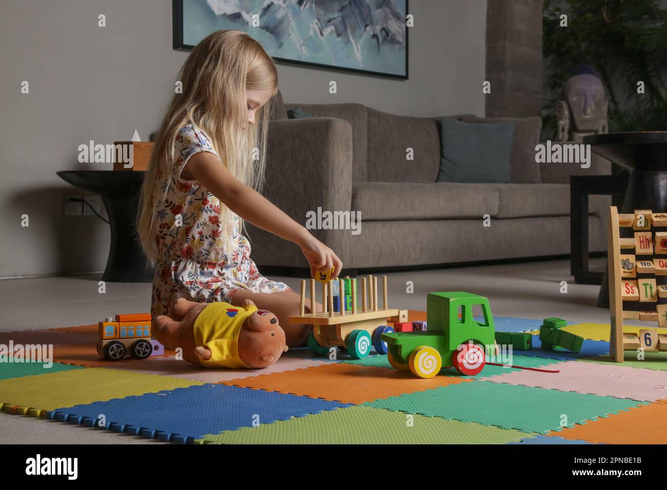 Adorable petite fille jouant avec des jouets en bois à la maison Banque D'Images