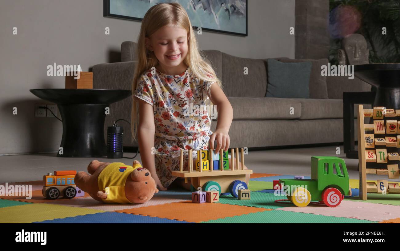 Adorable petite fille jouant avec des jouets en bois à la maison Banque D'Images