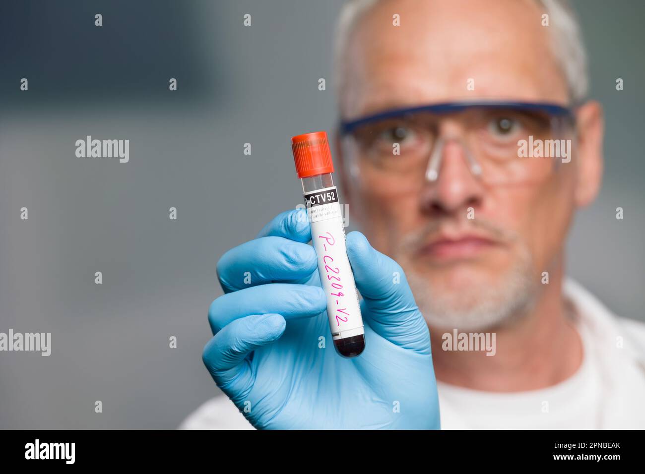 un médecin ou un scientifique manipule un tube de test sanguin devant une salle de laboratoire Banque D'Images