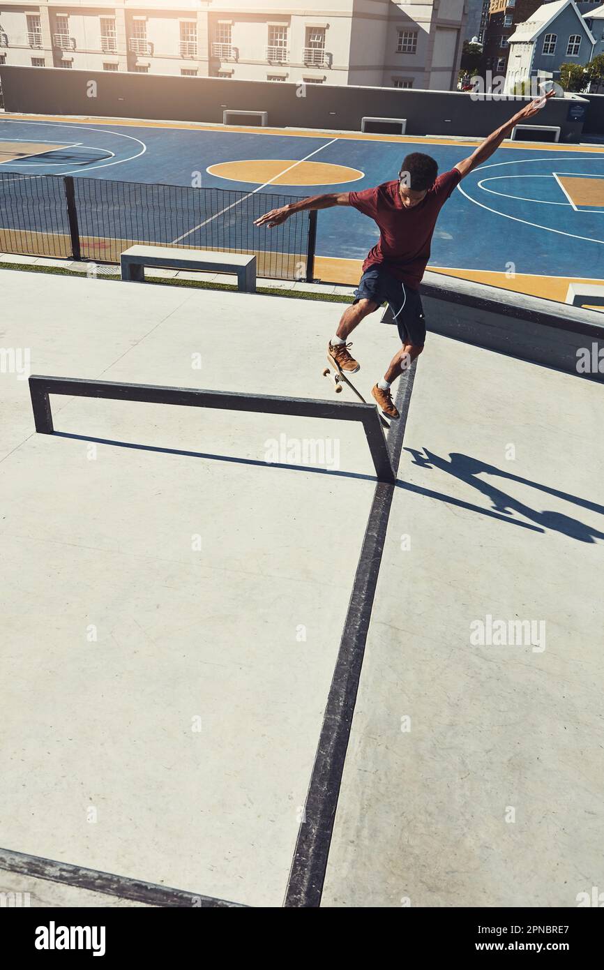 Rien ne peut le faire dérailler dans la vie. Photo en longueur d'un skateboarder faisant des tours sur un rail dans un parc de skate. Banque D'Images