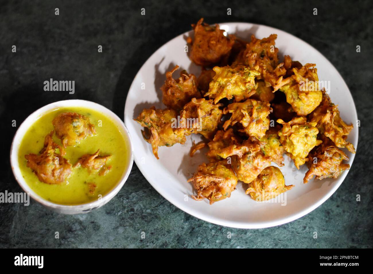 Gros plan de Kadhi Pakoda ou pakora et oignon frit conservés dans une assiette et un bol en céramique blanche, Bhaji kanda croustillant, cuisine indienne, Pune, Maharashtra, Inde Banque D'Images