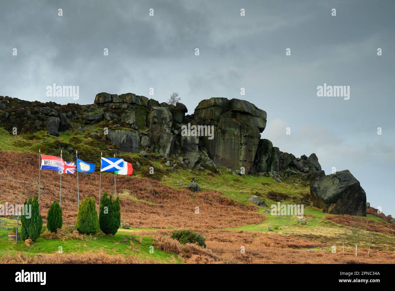 Nuages sombres au-dessus de Cow & Calf (rochers) et drapeaux sur les collines de la lande soufflant (site touristique populaire de la campagne) - Ilkley, West Yorkshire, Angleterre, Royaume-Uni. Banque D'Images