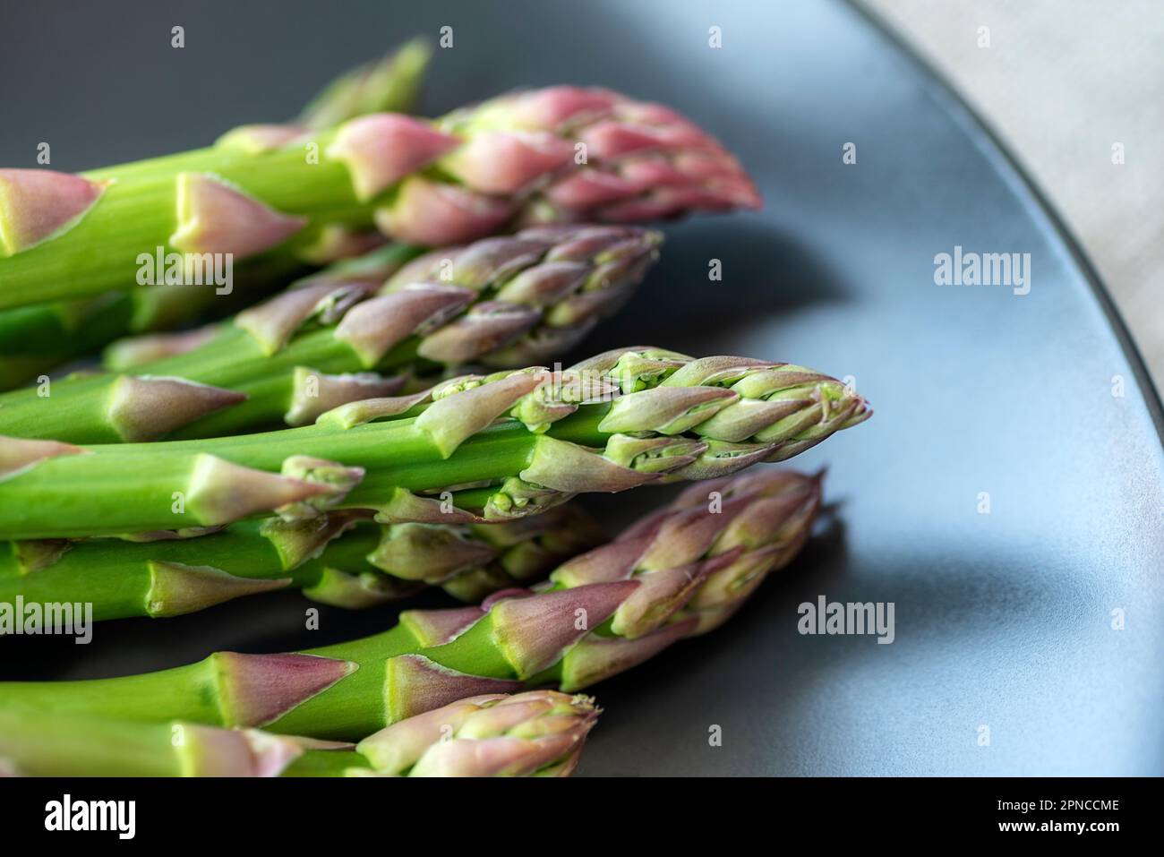 Asperges vertes fraîches sur une assiette noire. Concept alimentaire végétalien sain. Gros plan. Banque D'Images