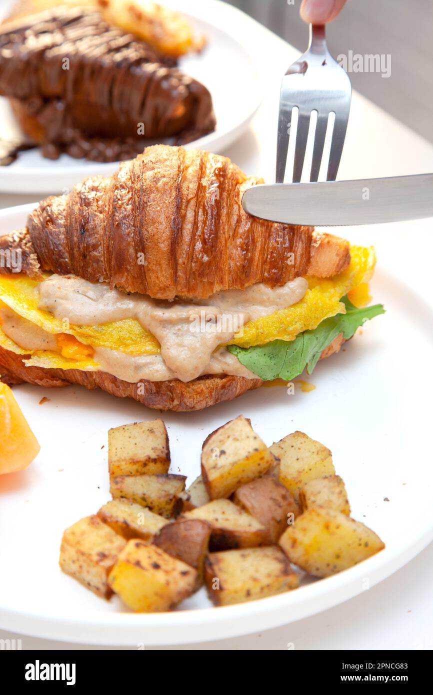 Petit-déjeuner avec croissants aux œufs, fruits de pastèque frais et pommes de terre. Banque D'Images