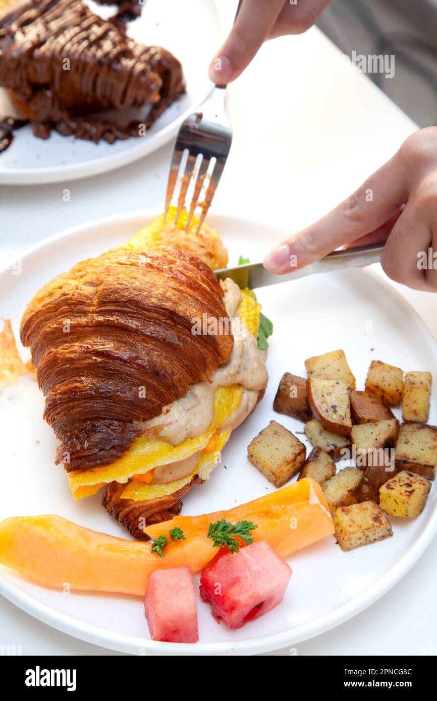 Petit-déjeuner avec croissants aux œufs, fruits de pastèque frais et pommes de terre. Banque D'Images