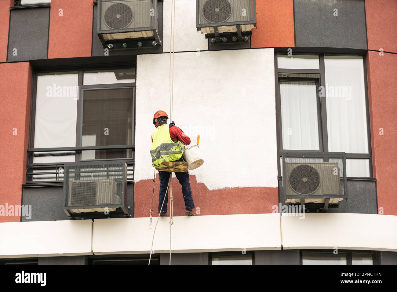 Les peintres-altitude modernisent la façade du bâtiment. Banque D'Images