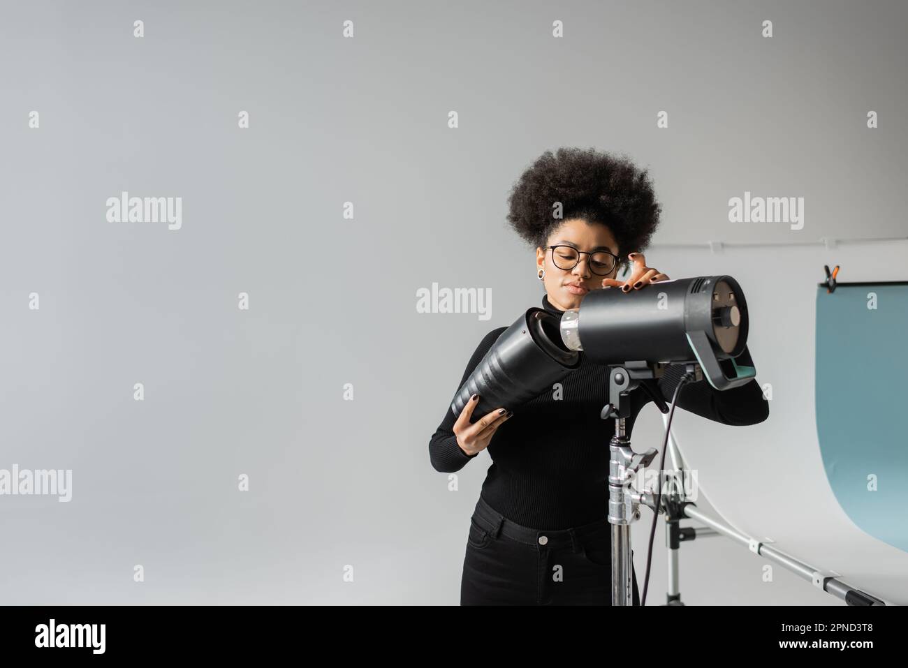 gestionnaire de contenu afro-américain assemblant lampe stroboscopique tout en travaillant en studio photo, image de stock Banque D'Images