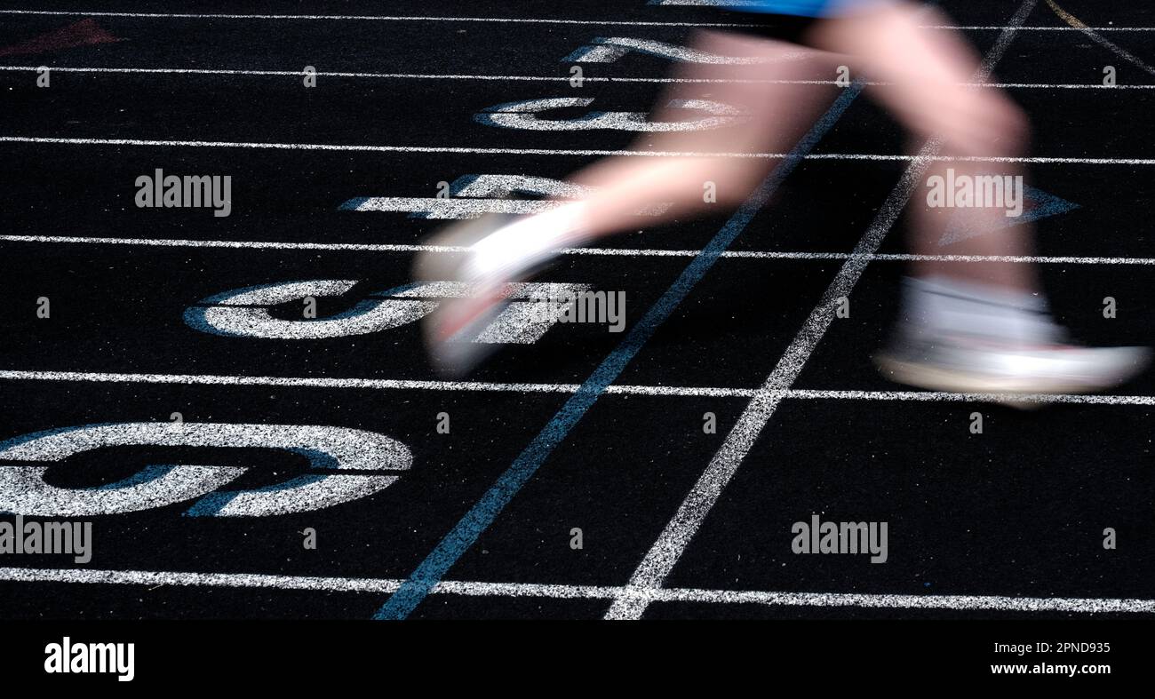 Coureur franchissant la ligne d'arrivée d'une course sur une piste, la course est floue rapidement Banque D'Images