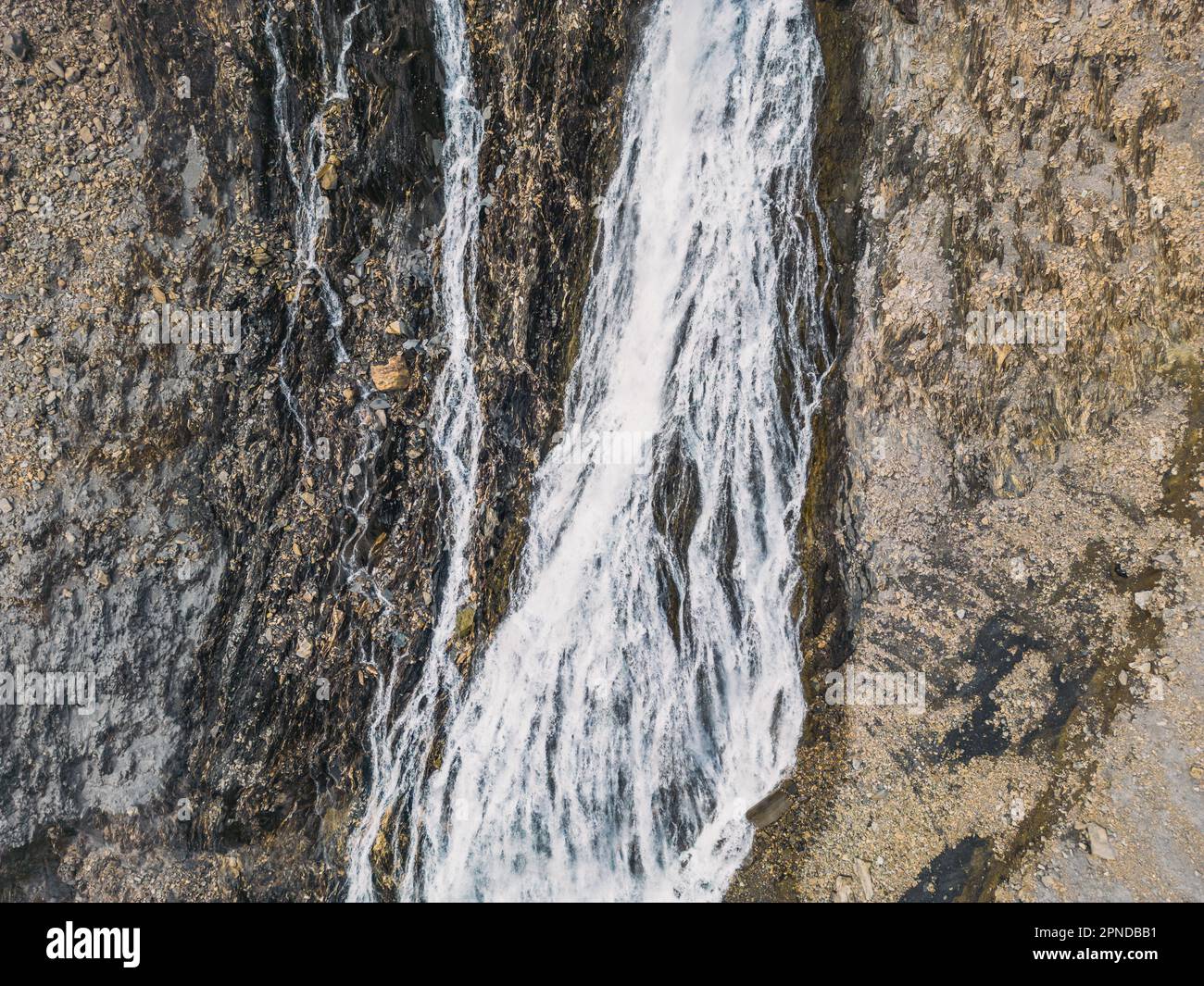 Tir de drone panoramique d'une cascade qui coule dans le lac Chambon dans les Alpes françaises Banque D'Images