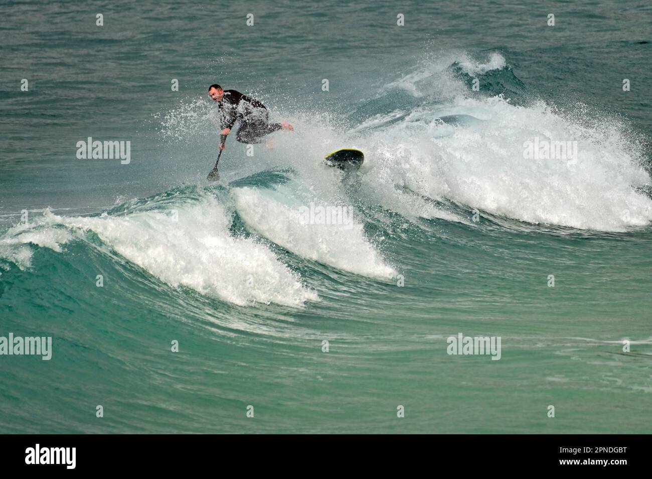 Cornwall, Royaume-Uni. 18th avril 2023. Au cours d'une après-midi chaude et venteuse à Sennen Cove, la maison de surf d'un surfeur Lone prend un Tumble. Crédit photo : Robert Timoney/Alay Live News Banque D'Images