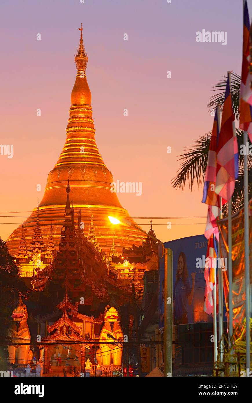 Le stupa géant de la pagode Shwedagon avec des drapeaux bouddhistes au premier plan au crépuscule, Yangon, Myanmar. Banque D'Images