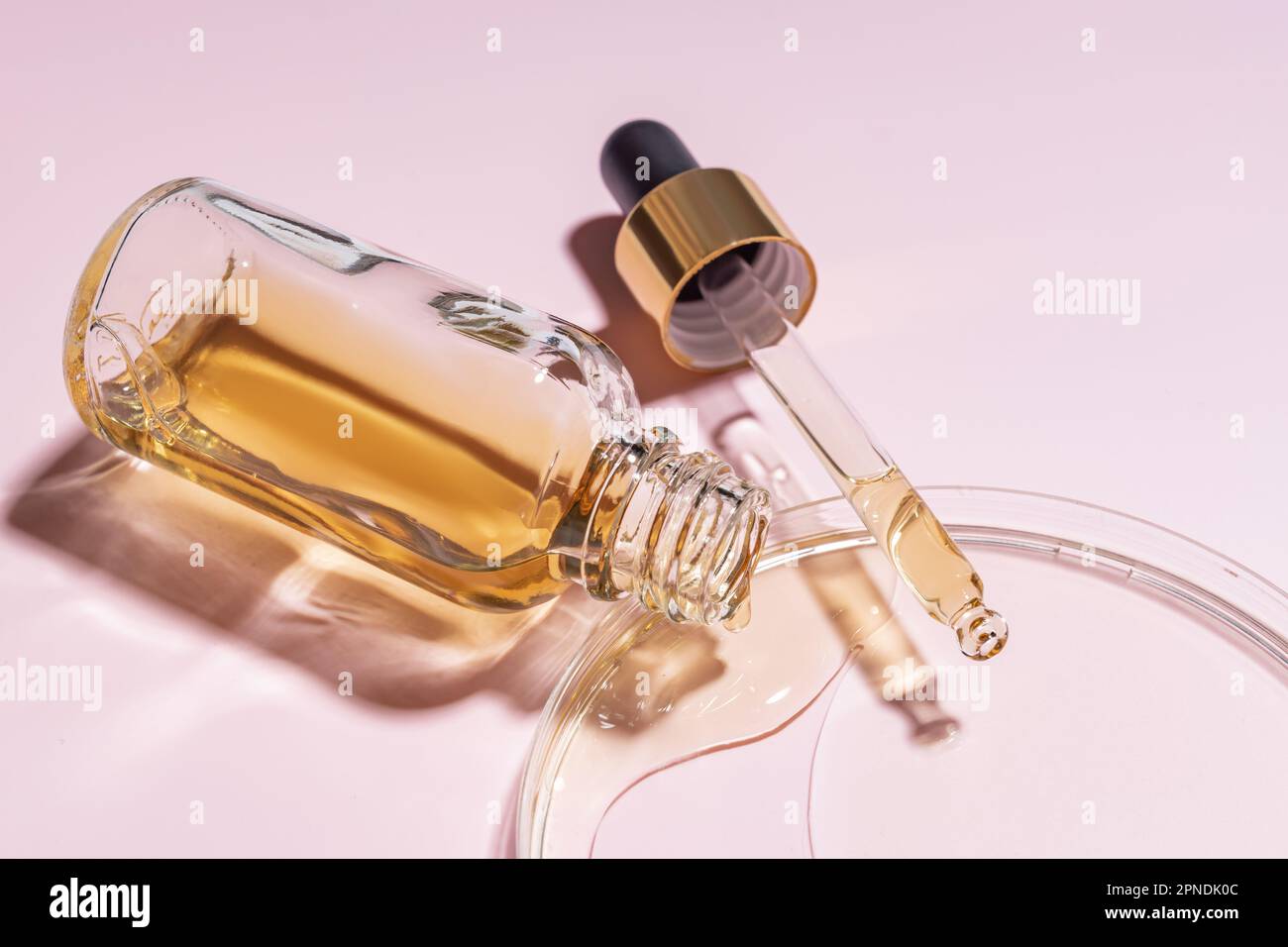 Maquette de marque de flacon en verre compte-gouttes. Pipette cosmétique. Fond rose tendance. Concept de cosmétiques biologiques et de beauté. Lumière intense du soleil. Caustique Banque D'Images