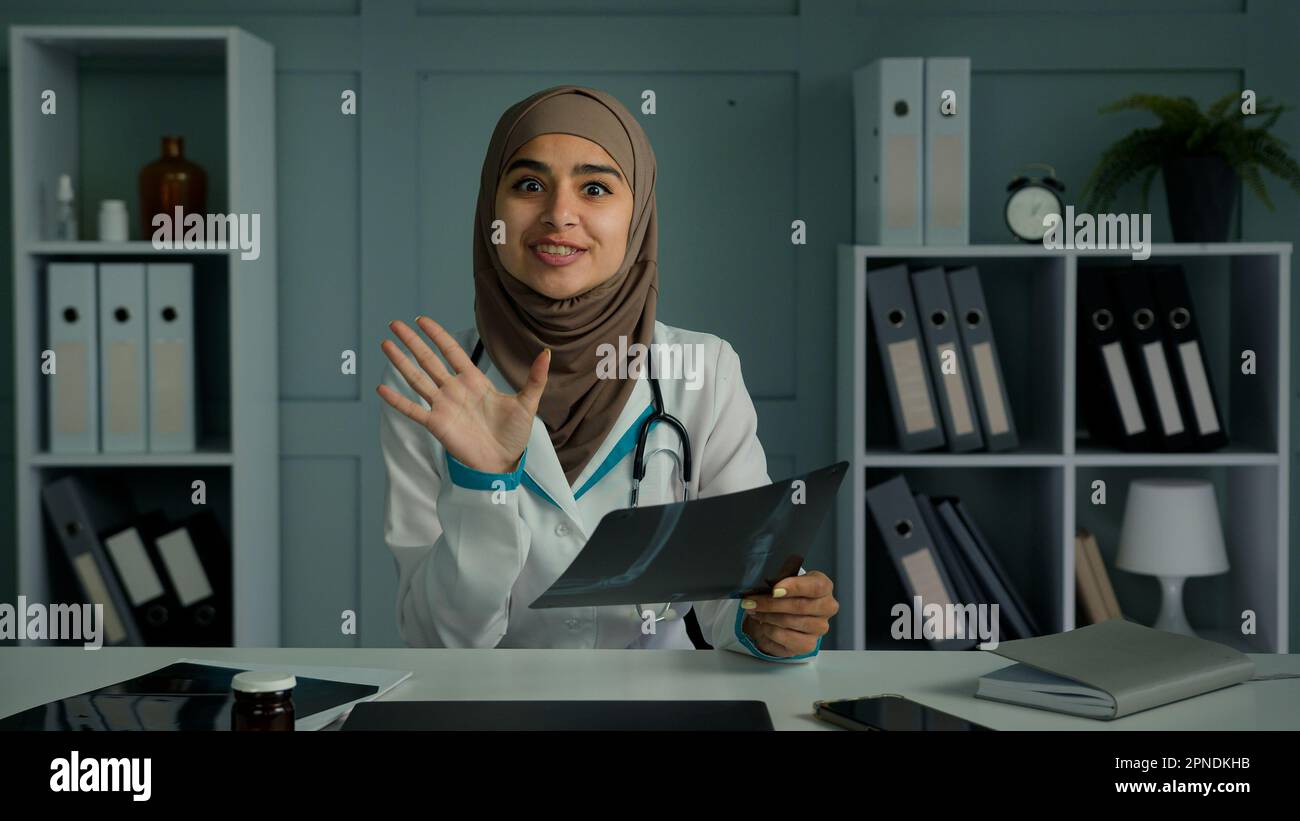 Médecin positif femme radiologue utiliser l'application de vidéoconférence parler avec le patient distant expliquer le résultat de la tomographie par IRM montrer l'image radiologique rendre virtuel Banque D'Images