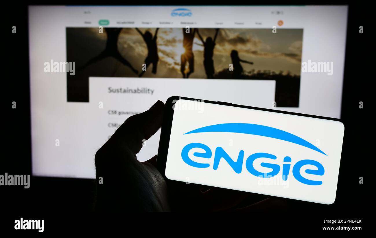 Personne tenant un smartphone avec le logo de la société française d'énergie Engie S.A. à l'écran devant le site. Mise au point sur l'affichage du téléphone. Banque D'Images