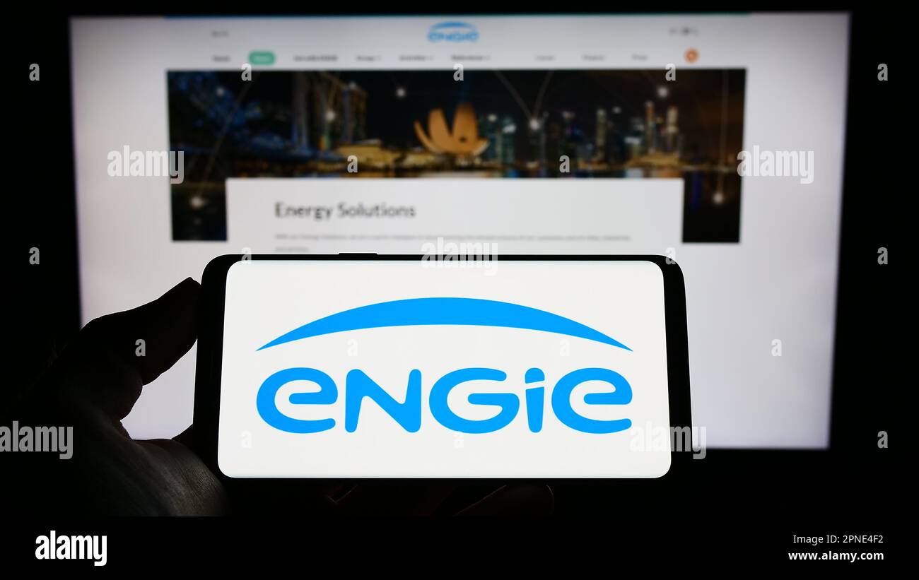 Personne tenant un téléphone portable avec le logo de la société française d'énergie Engie sa à l'écran en face de la page Web d'affaires. Mise au point sur l'affichage du téléphone. Banque D'Images