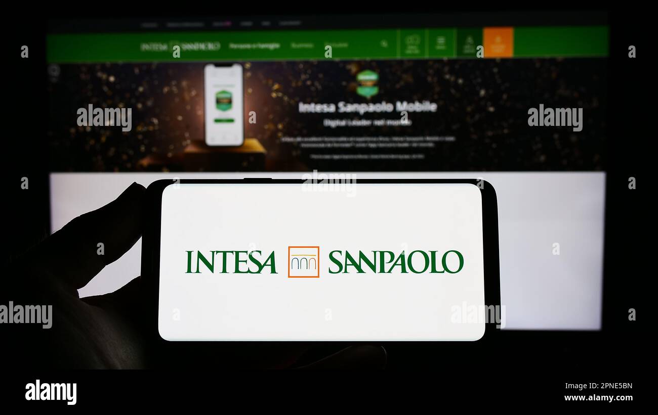 Personne tenant un smartphone avec le logo de la société bancaire italienne Intesa Sanpaolo S.p.A. à l'écran devant le site Web. Mise au point sur l'affichage du téléphone. Banque D'Images