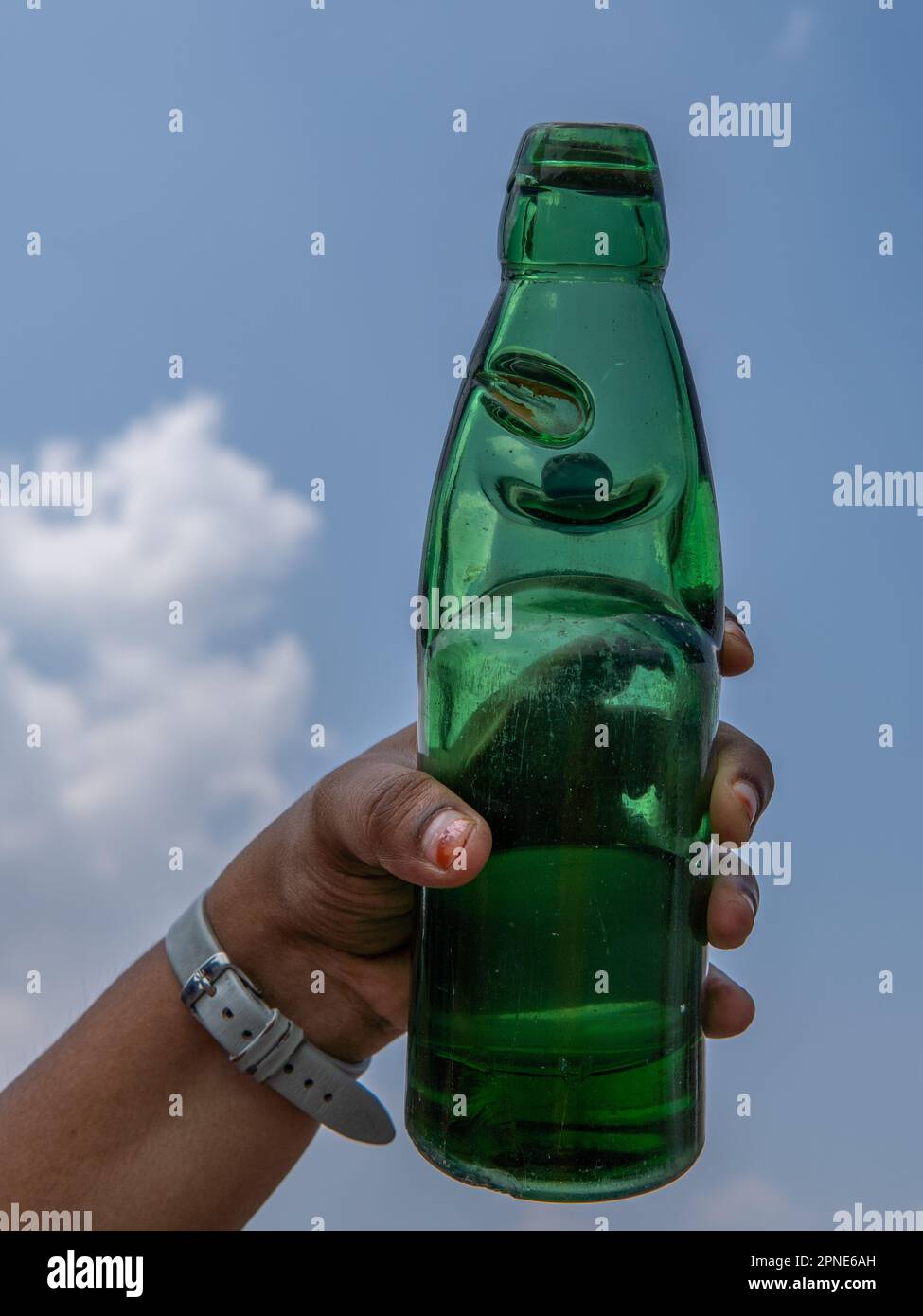 Une jeune femme tenant une bouteille de soda de goli un beau jour. bouteille de soda avec bouchon circulaire en marbre. Une boisson traditionnelle rafraîchissante Banque D'Images