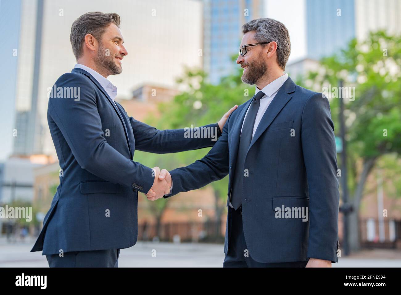 Un homme d'affaires américain qui se fait la main avec un partenaire. Deux hommes d'affaires qui se secouent à l'extérieur. Serrer les mains. Stratégie de gestion. Liaison entre deux bus Banque D'Images