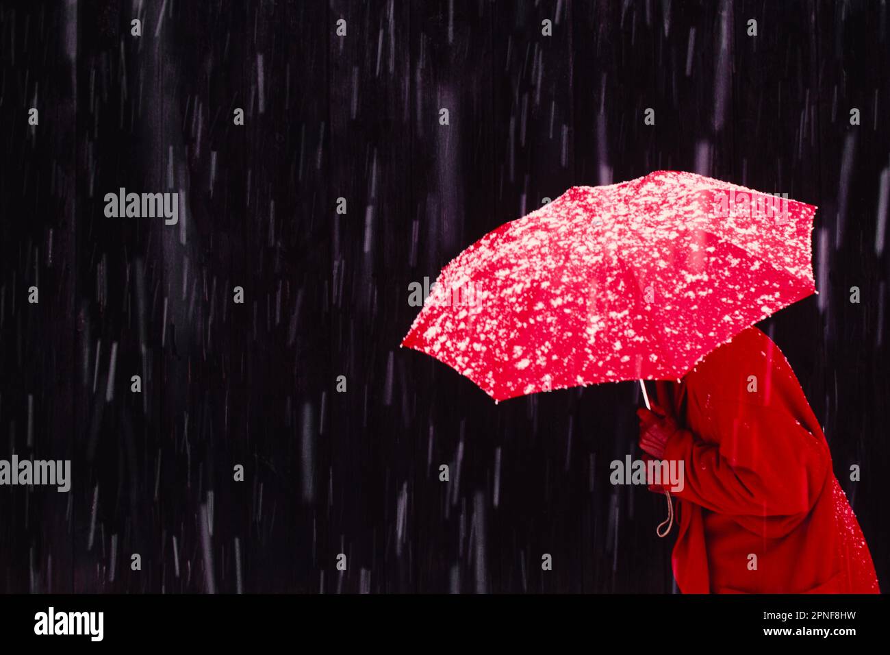 Femme marchant dans la tempête de neige avec un parapluie rouge Banque D'Images