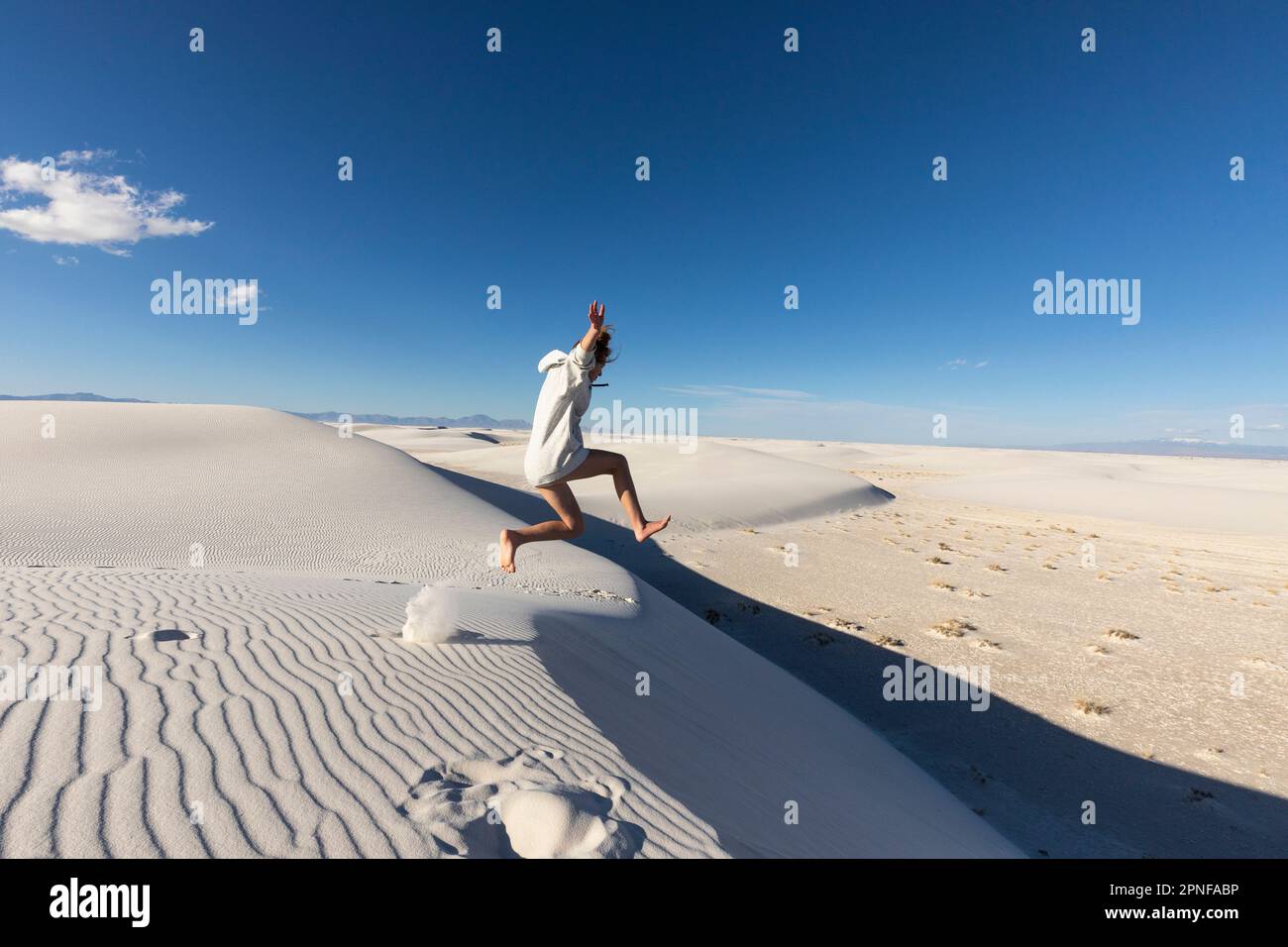 États-Unis, Nouveau-Mexique, parc national de White Sands, jeune fille qui bondit sur des dunes de sable Banque D'Images