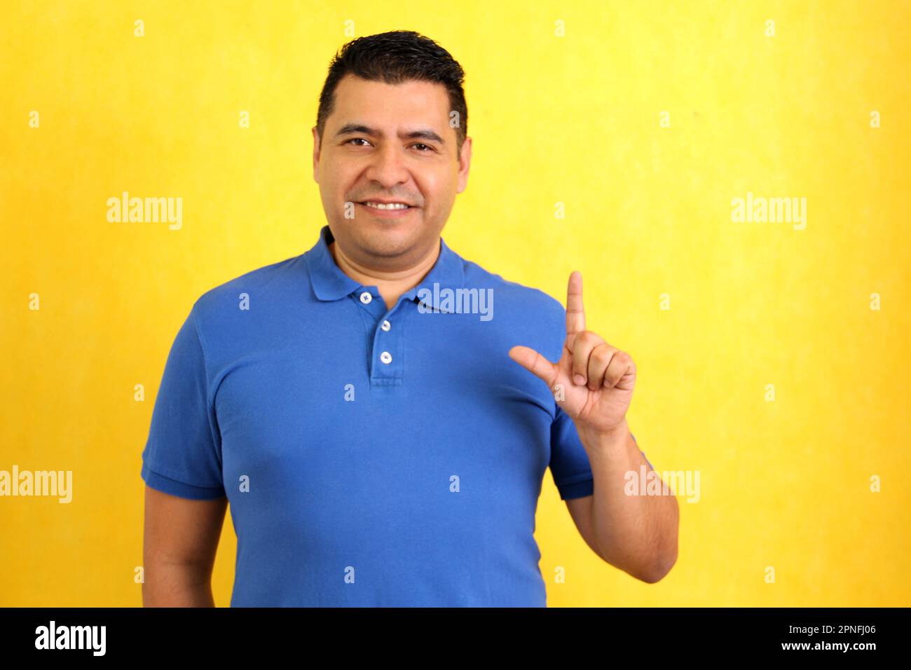 L'homme adulte Latino à poil sombre utilise le langage des signes typique des personnes sourdes pour établir un canal de communication avec son environnement social Banque D'Images