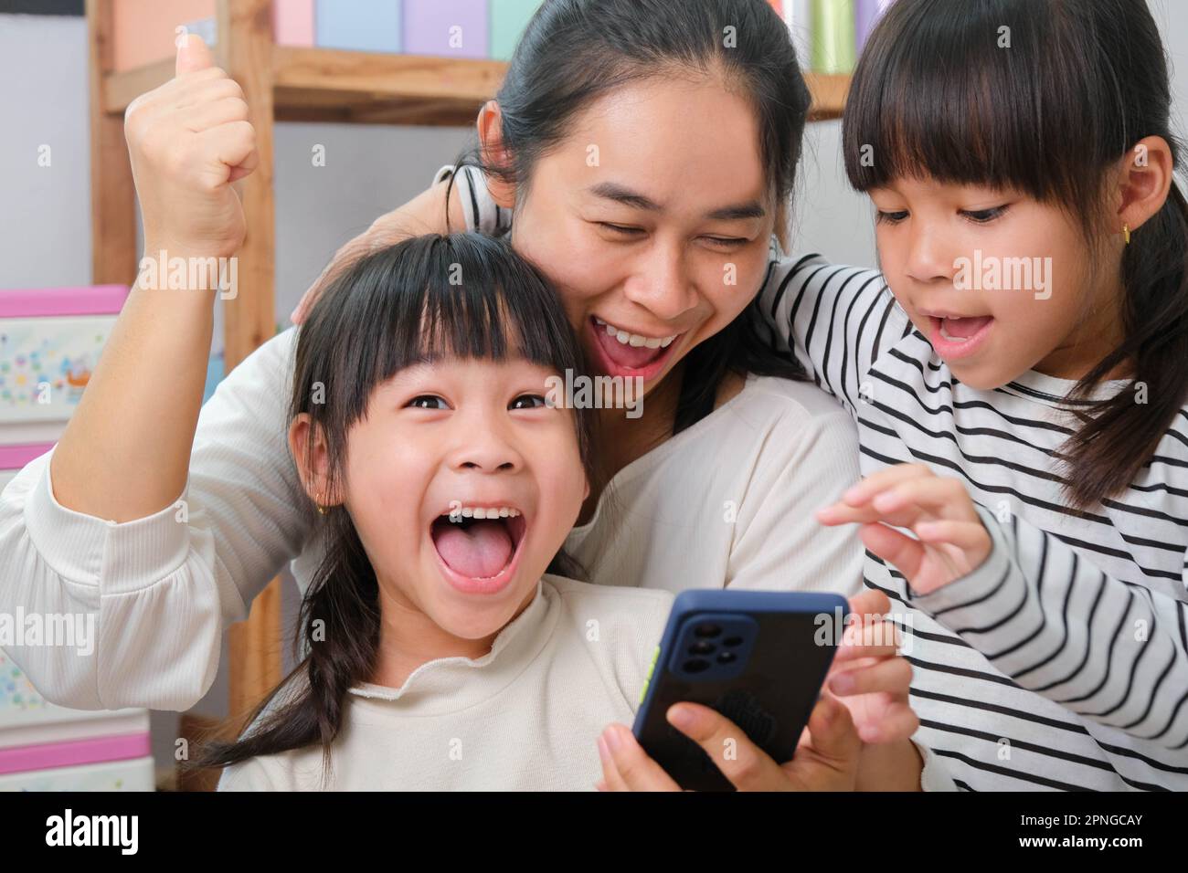 Mère et fille jouant et embrassant, prenant des selfies sur des smartphones, regardant des dessins animés ou jouant à des jeux en ligne à la maison. Bonne famille aimante et mot Banque D'Images