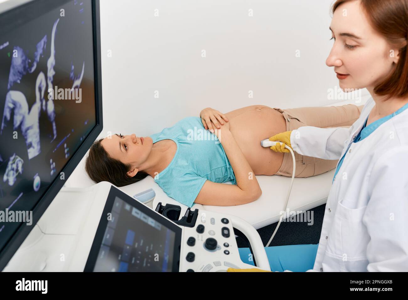 Tests prénatals. Spécialiste de l'échographie effectuant le dépistage du troisième trimestre de la femme enceinte avec un échographe en clinique médicale Banque D'Images