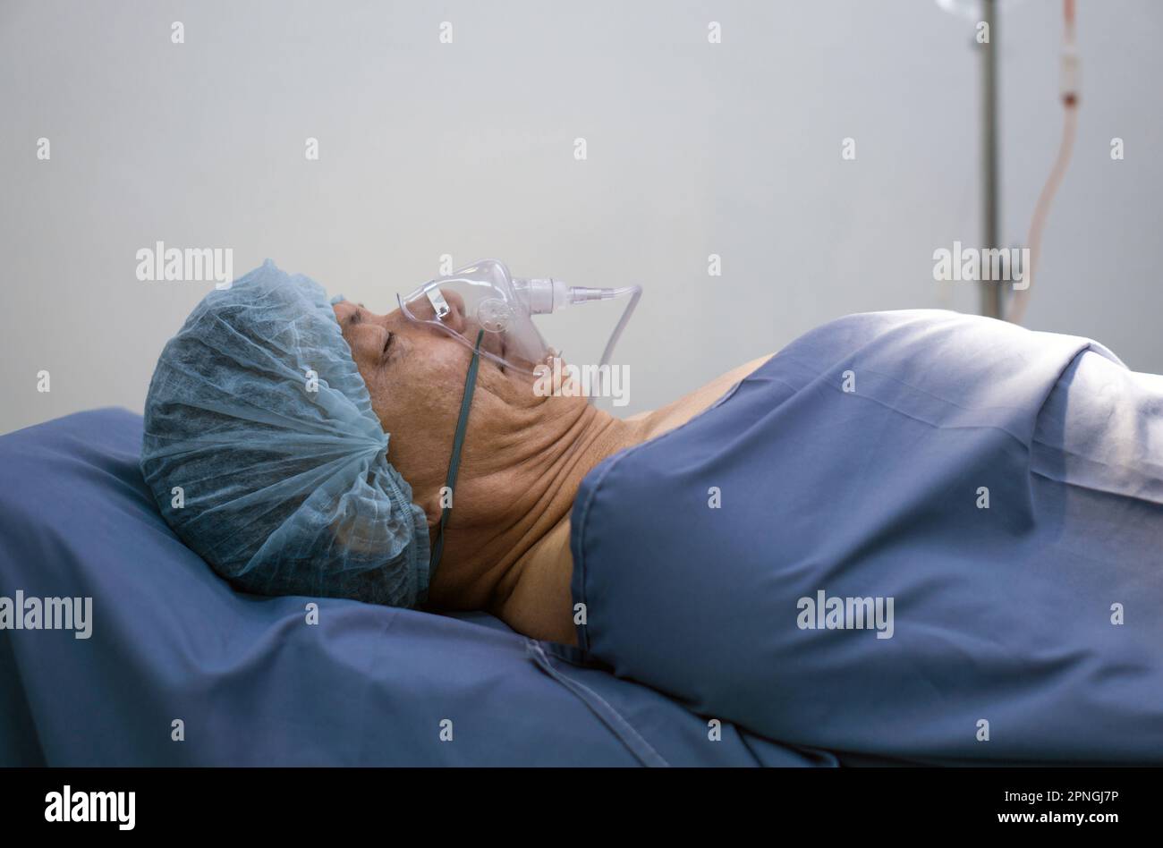 Patient asiatique âgé qui respire avec un respirateur, allongé sur un lit d'hôpital dans la salle d'opération en attente d'une opération chirurgicale. Banque D'Images