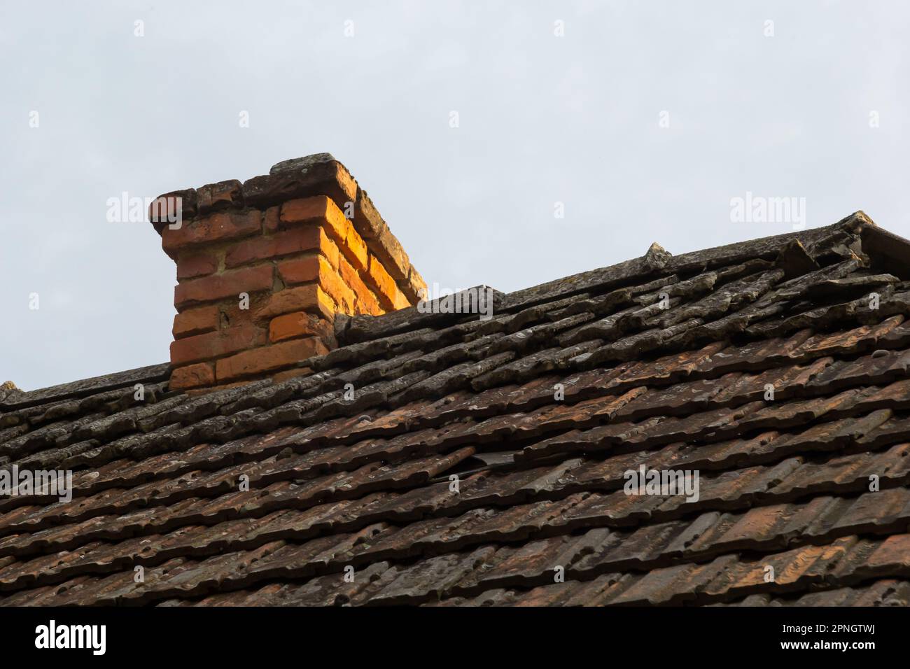 cheminée en brique rouge en haut de la maison du village. Un toit en tuiles sur le fond du ciel. Banque D'Images