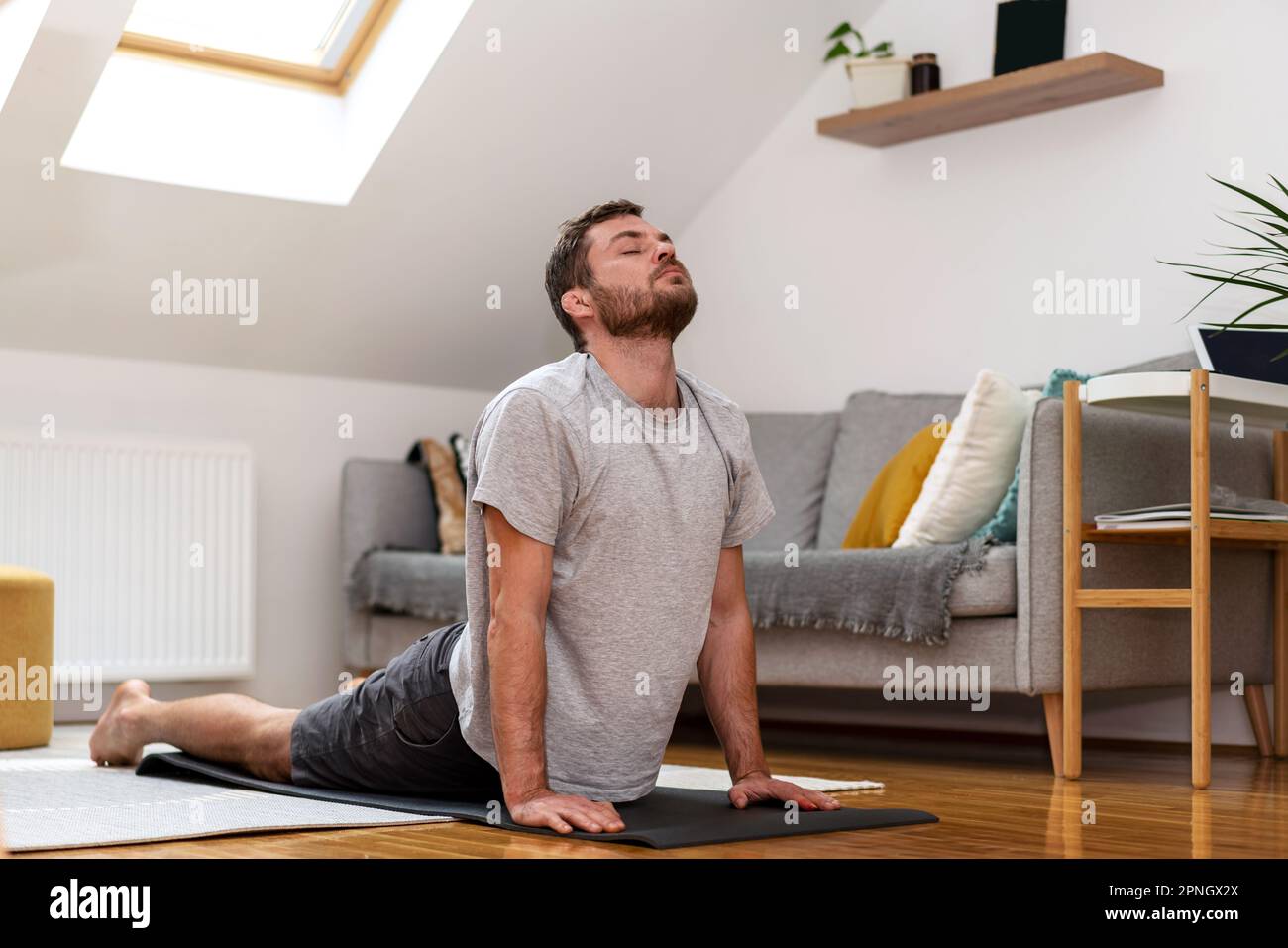 Lutteur avec des oreilles cassées faisant de l'exercice d'étirement sur le tapis de yoga à la maison. Banque D'Images