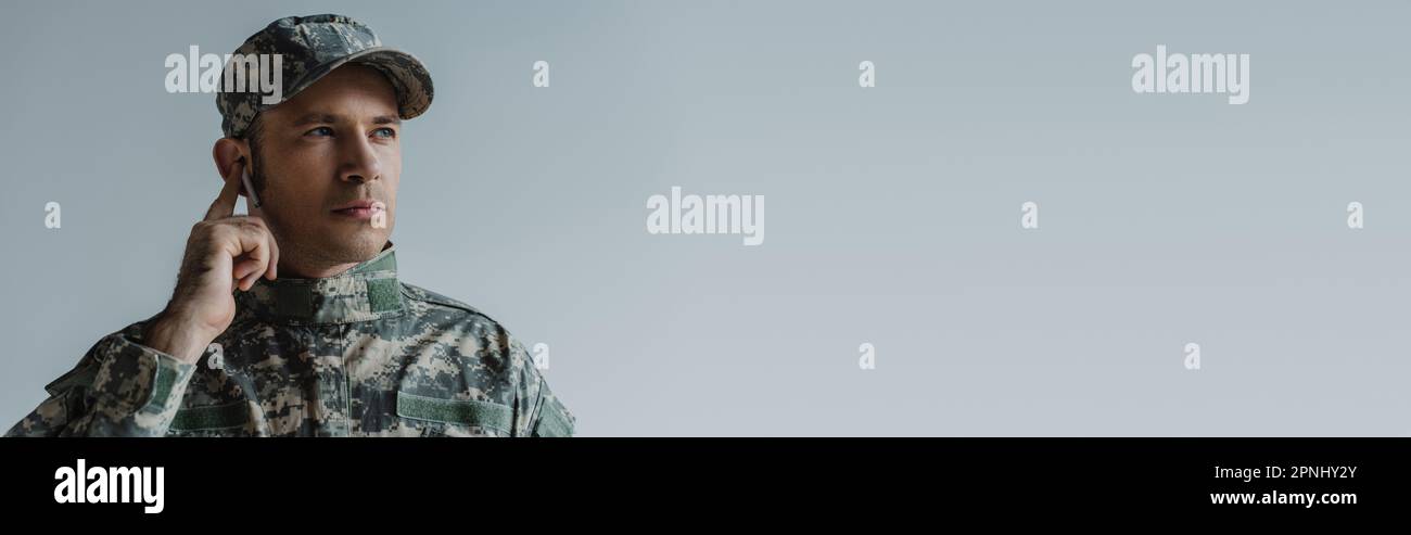 soldat en uniforme et casque réglable sans fil écouteurs isolés sur  bannière grise Photo Stock - Alamy