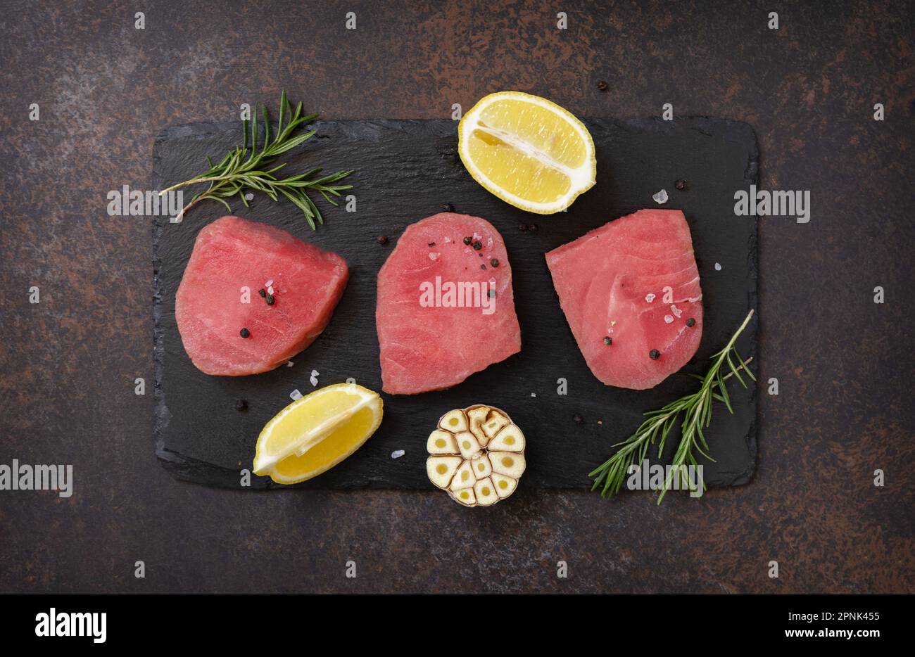Fruits de mer. Steaks de thon juteux cru aux épices et au romarin sur une table en pierre. Vue de dessus. Banque D'Images
