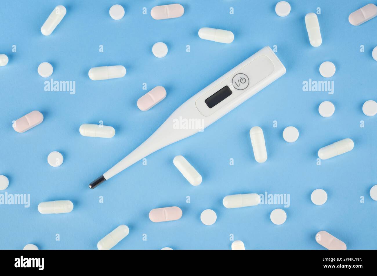 Thermomètre numérique avec pilules sur fond bleu. Concept médical Banque D'Images