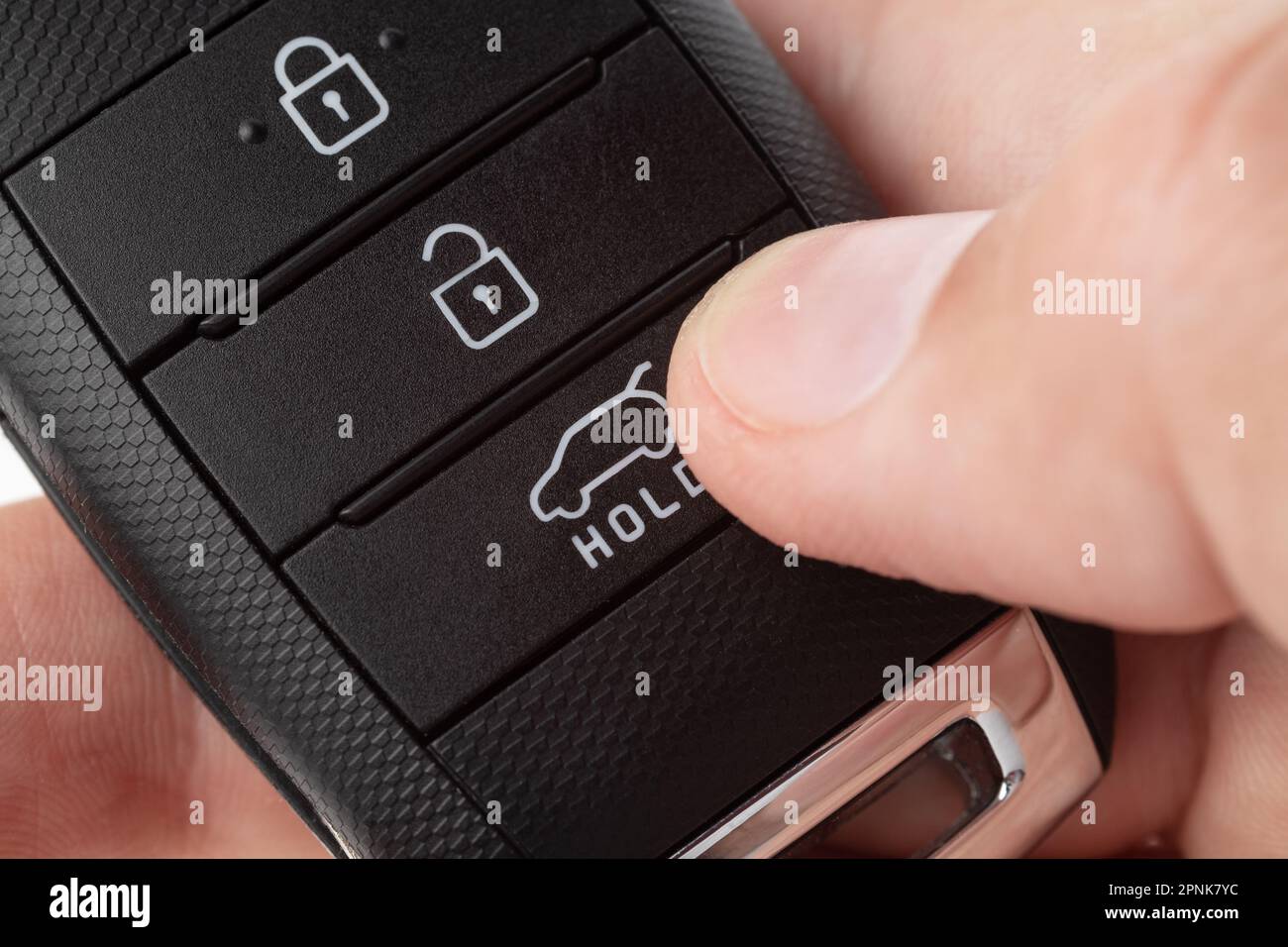 Ouvrez le coffre d'une voiture à l'aide du bouton situé sur le porte-clés. la main de l'homme tient la clé de la voiture sur fond blanc gros plan. Banque D'Images
