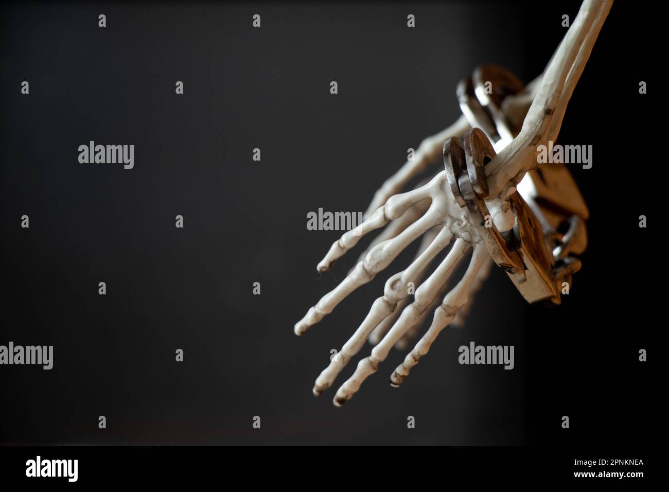 Mains d'un squelette dans les menottes sur un fond noir Banque D'Images