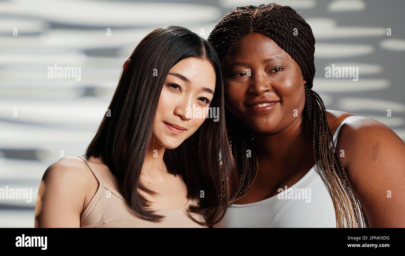 Femmes avec différents types de corps posant en studio, montrant la positivité et la confiance en soi. Diverses filles exprimant le bien-être et la féminité, riant et se sentant belle, skintones diversité. Banque D'Images