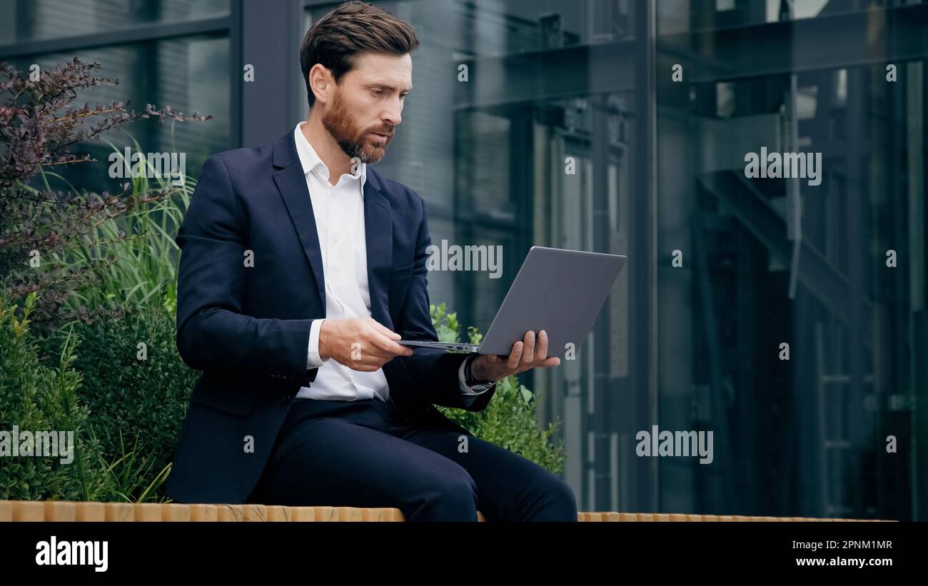 Professionnel consultant homme d'affaires assis à l'extérieur communiquer par appel vidéo sur ordinateur portable client de conseil à la conférence en ligne parler via webcam Banque D'Images