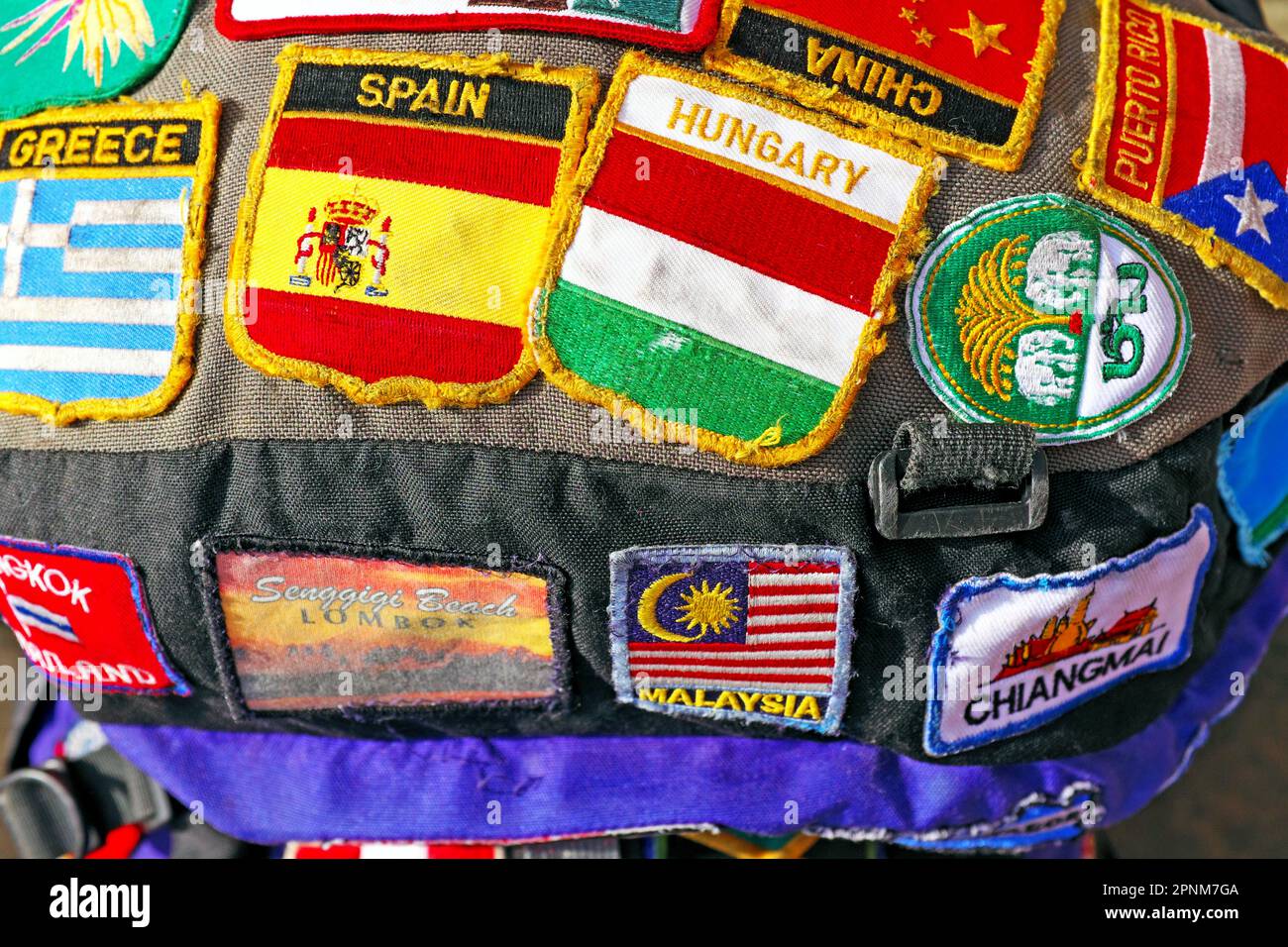Le haut d'un sac à dos de voyage autonome couvert en cousu sur des patchs identifiant les destinations visitées. Les patchs sont une forme d'identité pour le routard. Les correctifs incluent des destinations en provenance d'Europe, d'Asie et des Caraïbes. Banque D'Images