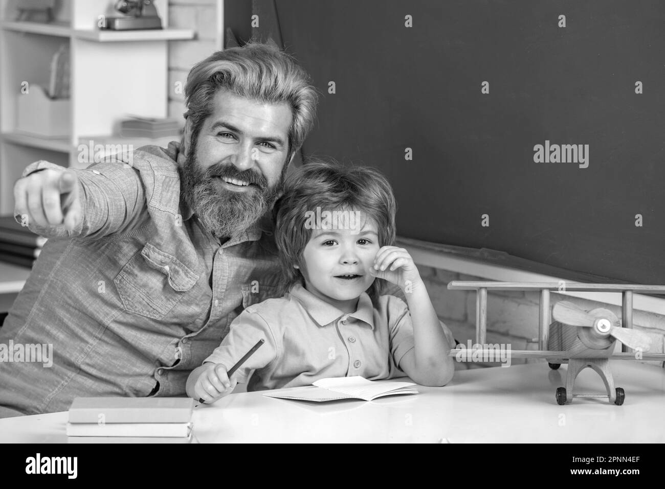 Un enfant mignon avec un enseignant dans la salle de classe près du bureau du tableau noir. Agence de tutorat. Tutorat privé pour les enfants. Modèles de partenariat avec la communauté scolaire. Banque D'Images