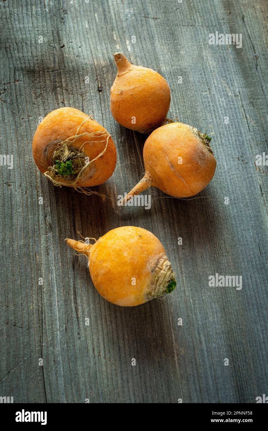 Groupe de navets frais et orange affichés sur une table en bois rustique Banque D'Images