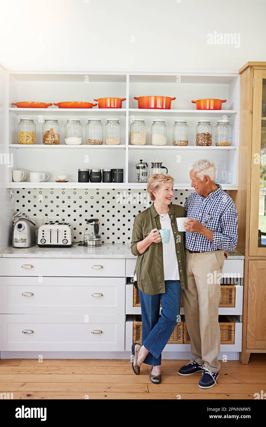 Le café est le secret de cette lueur jeune. un heureux couple senior se liant sur le café dans leur cuisine à la maison. Banque D'Images